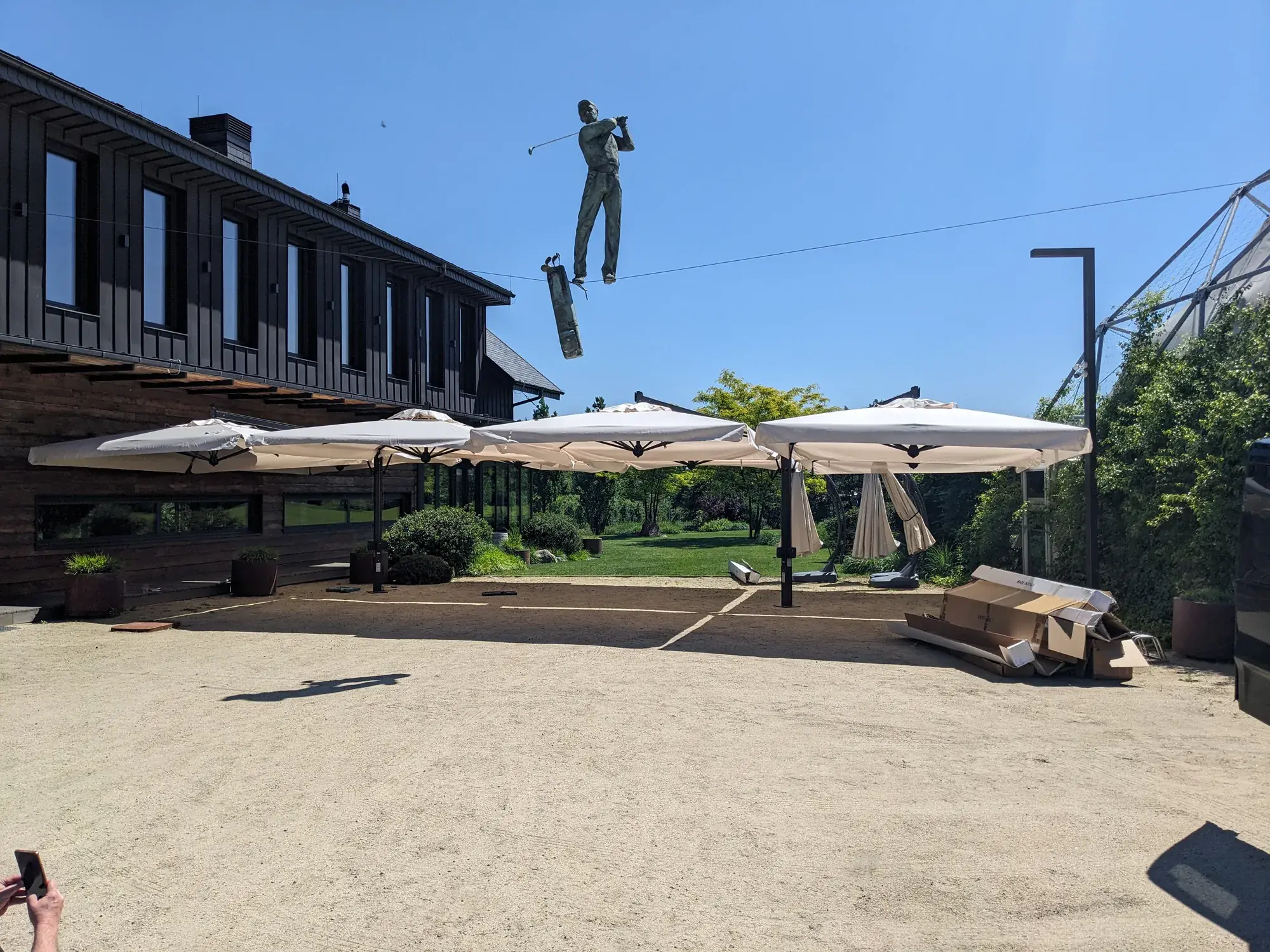 Karma House terrace with Alu Poker 6×6 m parasols and a golfer sculpture