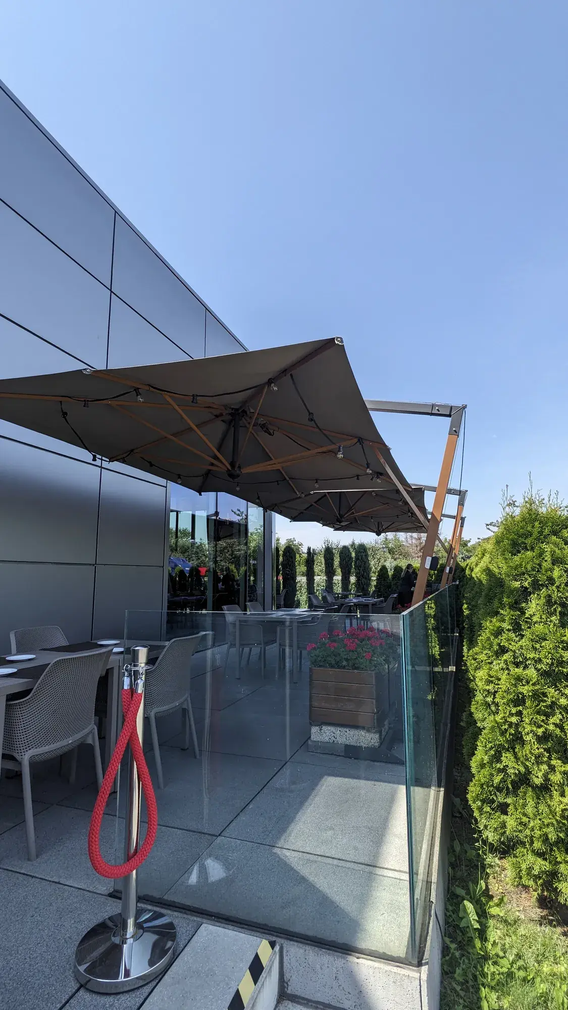 Torino Braccio parasol with wooden ribs over tables by the glass balustrade
