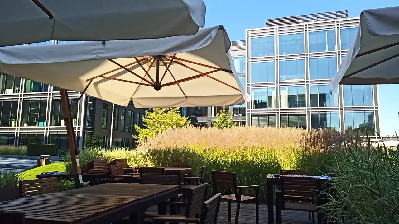 Slunečníky Palladio Braccio nad stoly mezi vysokými travami v The Park Warsaw
