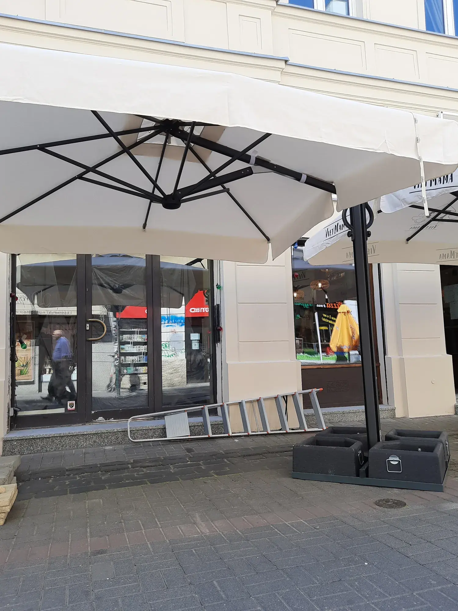 Galaxia Dual parasol with a weighted base in front of the Viet Mama restaurant window