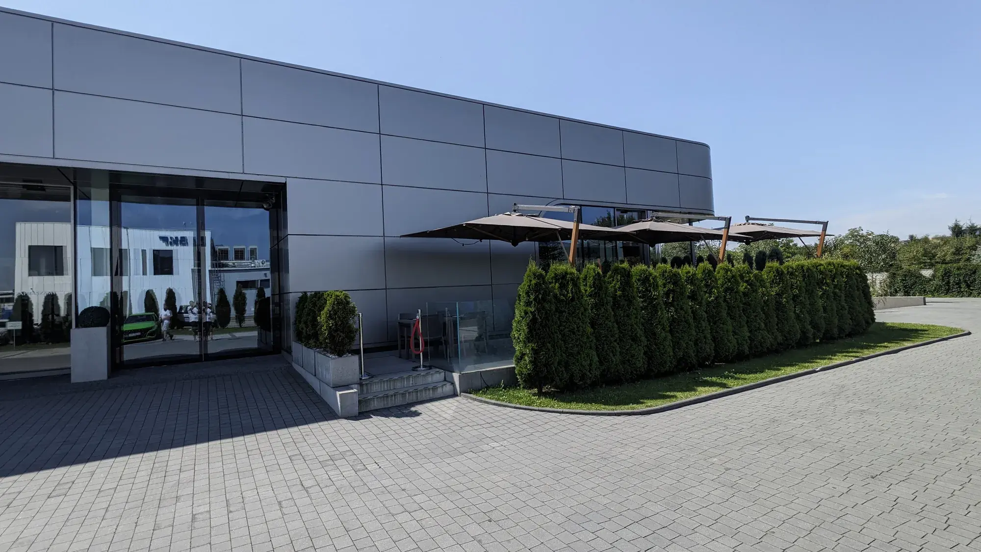 Roh terasy La Squadra se slunečníky Torino Braccio za živým plotem
