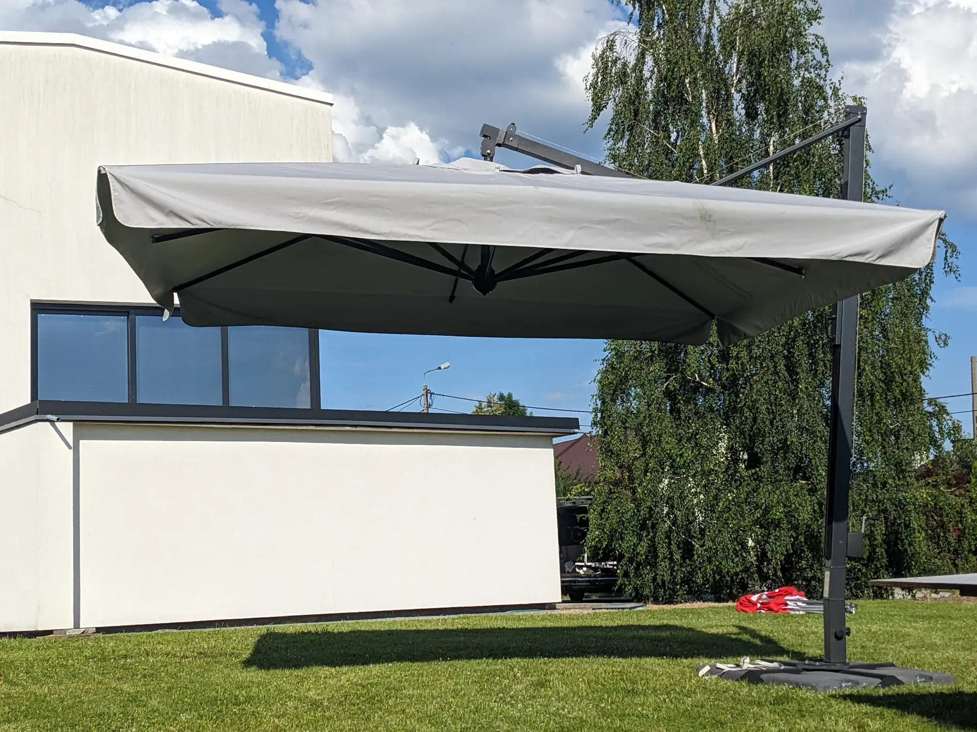 Galileo Maxi Dark side-post parasol over the lawn by a house in Bielsko-Biała