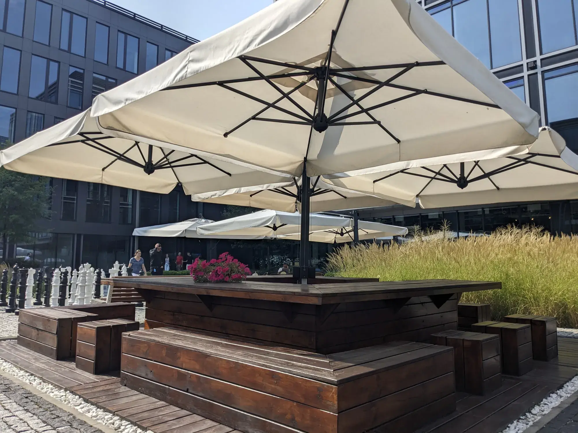 Sonnenschirm Alu Poker/Double Dark mit vier Bespannungen über Holztischen im Patio von The Park Warsaw